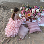 Blush pink organza girls formal dress with the train spread across the sand, angled view, for a portrait session.