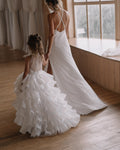 White organza flower girl dress with a sheer button back and a ruffled train, back view, for a ceremony.