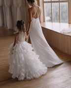 White organza flower girl dress with a sheer button back and a ruffled train, back view, for a ceremony.