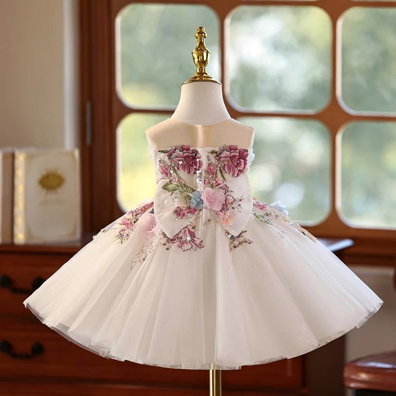 Back view of the ivory floral girls party dress, showing the sequinned bow over the back zip closure.