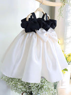Ivory and black satin girls party dress with a gathered black ruffle band and a full skirt, designed for first birthdays and weddings.