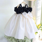 Ivory and black satin girls party dress with a large ivory back bow, designed for weddings and parties.