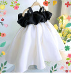 Ivory and black satin girls party dress with an off-shoulder ruffle bodice, designed for first birthdays and photoshoots.