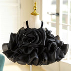 Black organza girls party dress with an oversized rosette bodice, velvet straps and a ruffled tutu skirt, designed for birthdays and holiday parties.