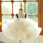 Ivory organza girls party dress with an oversized rosette bodice, black velvet straps and a ruffled tutu skirt, designed for birthdays and photoshoots.