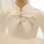 Ivory satin girls dress close-up with stand collar, crochet-trimmed lace yoke and pearl-center satin bow, designed for weddings.