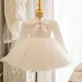 Ivory satin girls tutu dress with a stand collar, lace yoke, pearl-center bow and long sleeves, designed for weddings and first birthdays.