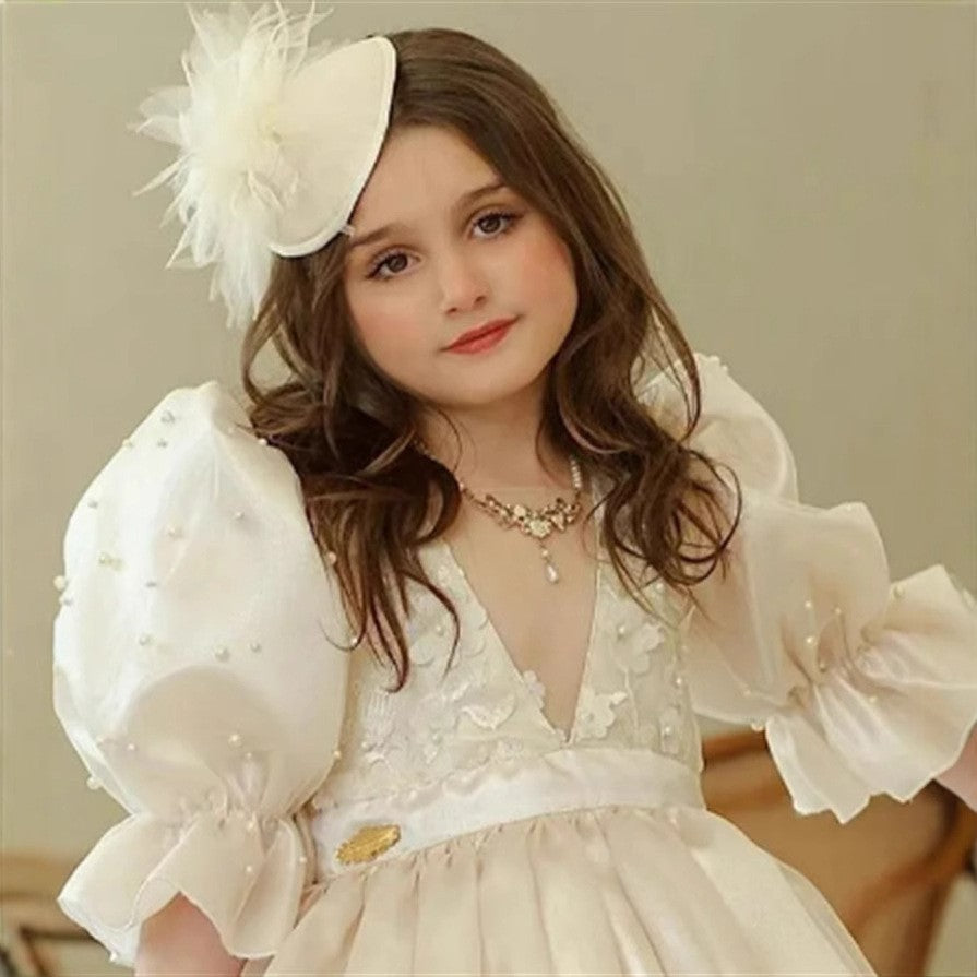 Close-up of the pearl beading and floral lace on the bodice of this white dress for girls.