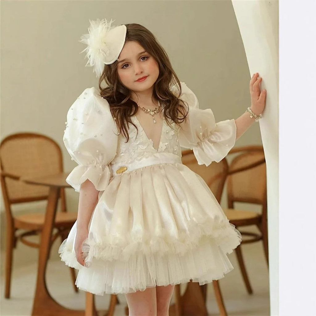Ivory pearl lace flower girl dress with puff sleeves and a satin sash, front view, for a wedding.