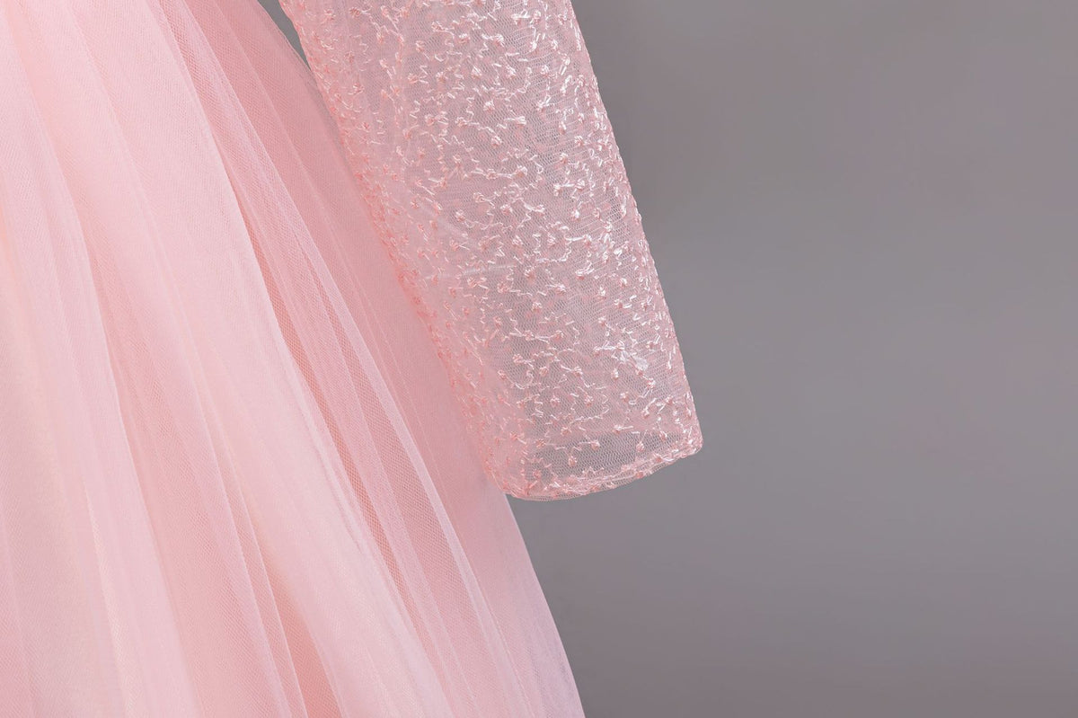 Pink lace and tulle girls gown with long sheer lace sleeves over a full tulle skirt, designed for weddings and flower girls.