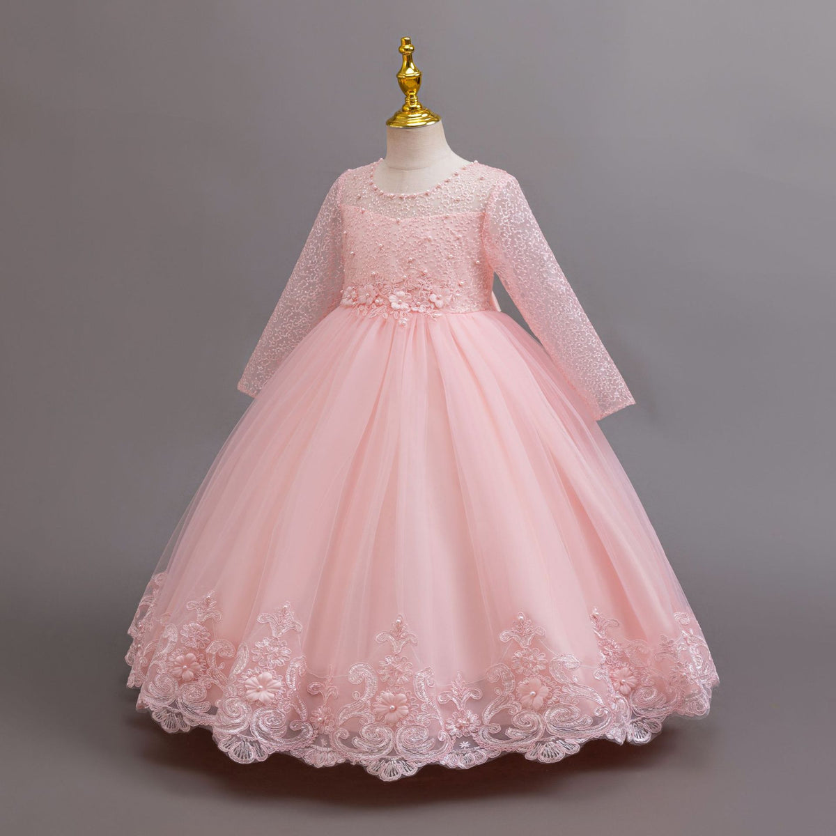 Pink lace and tulle girls gown with long lace sleeves and a floral waist, designed for weddings and flower girls.