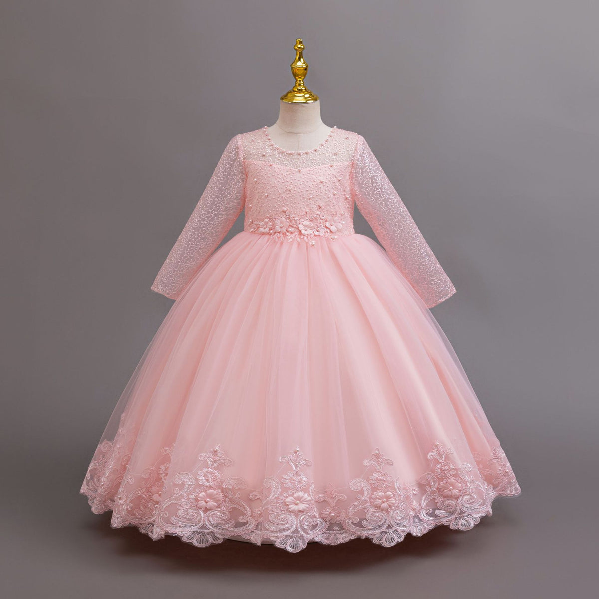 Pink lace and tulle girls gown with long lace sleeves, a pearl-beaded bodice and a lace hem, designed for weddings and flower girls.