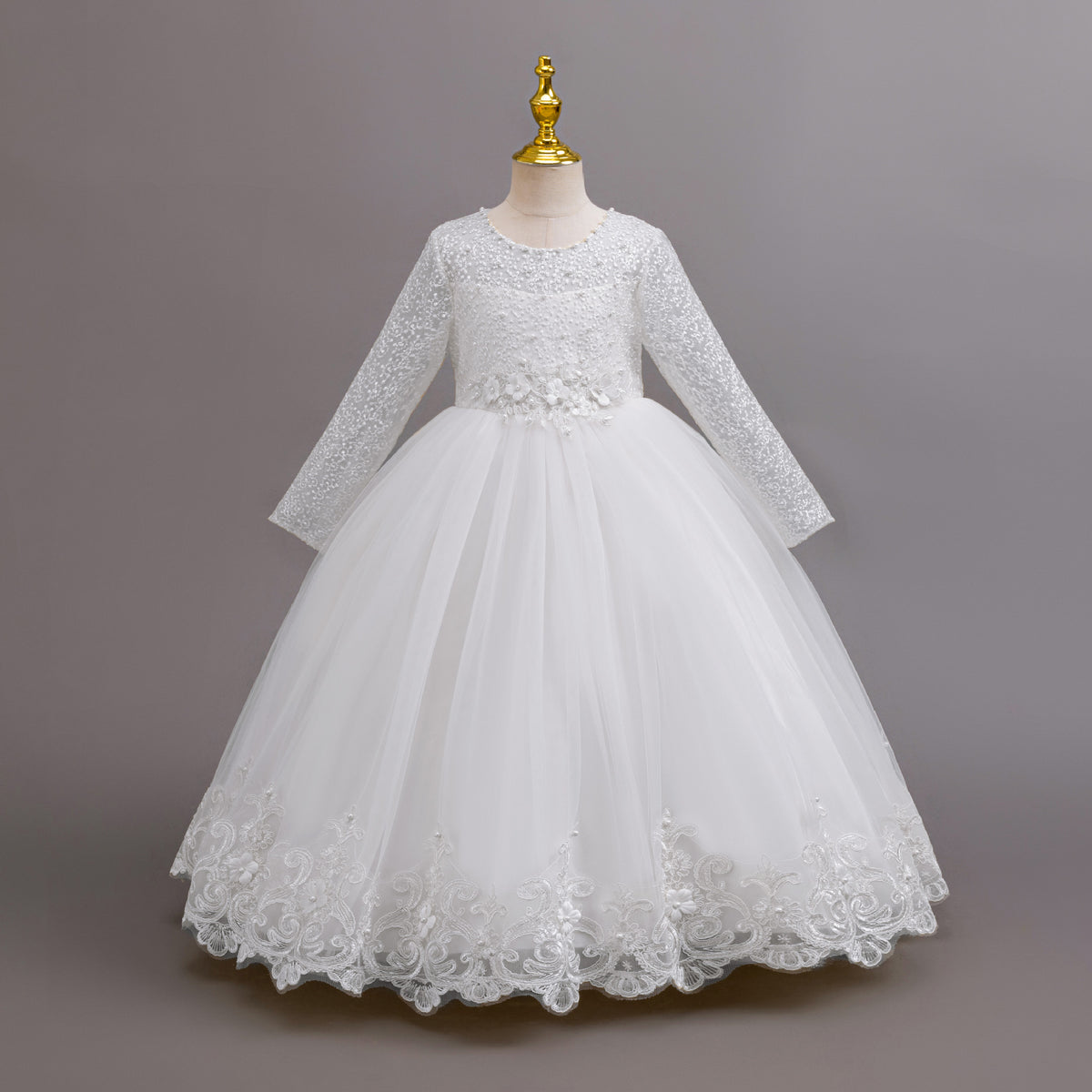 White lace and tulle girls gown with long lace sleeves, a pearl-beaded bodice and a lace hem, designed for weddings and flower girls.
