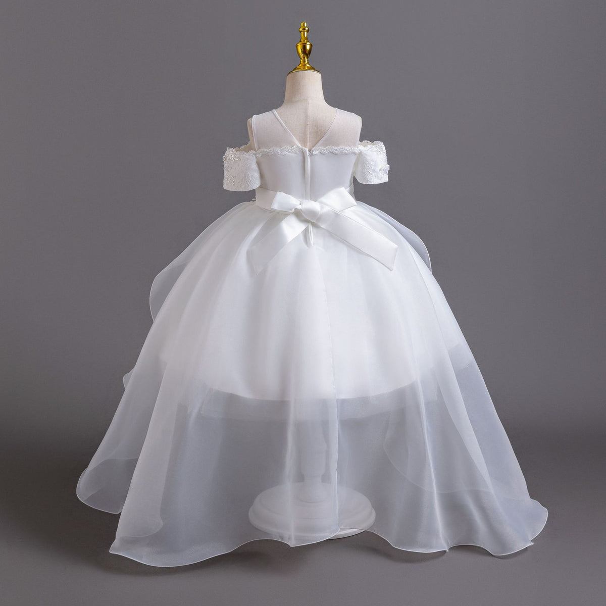 White lace girls gown back view with satin bow and organza train, designed for flower girls at weddings.