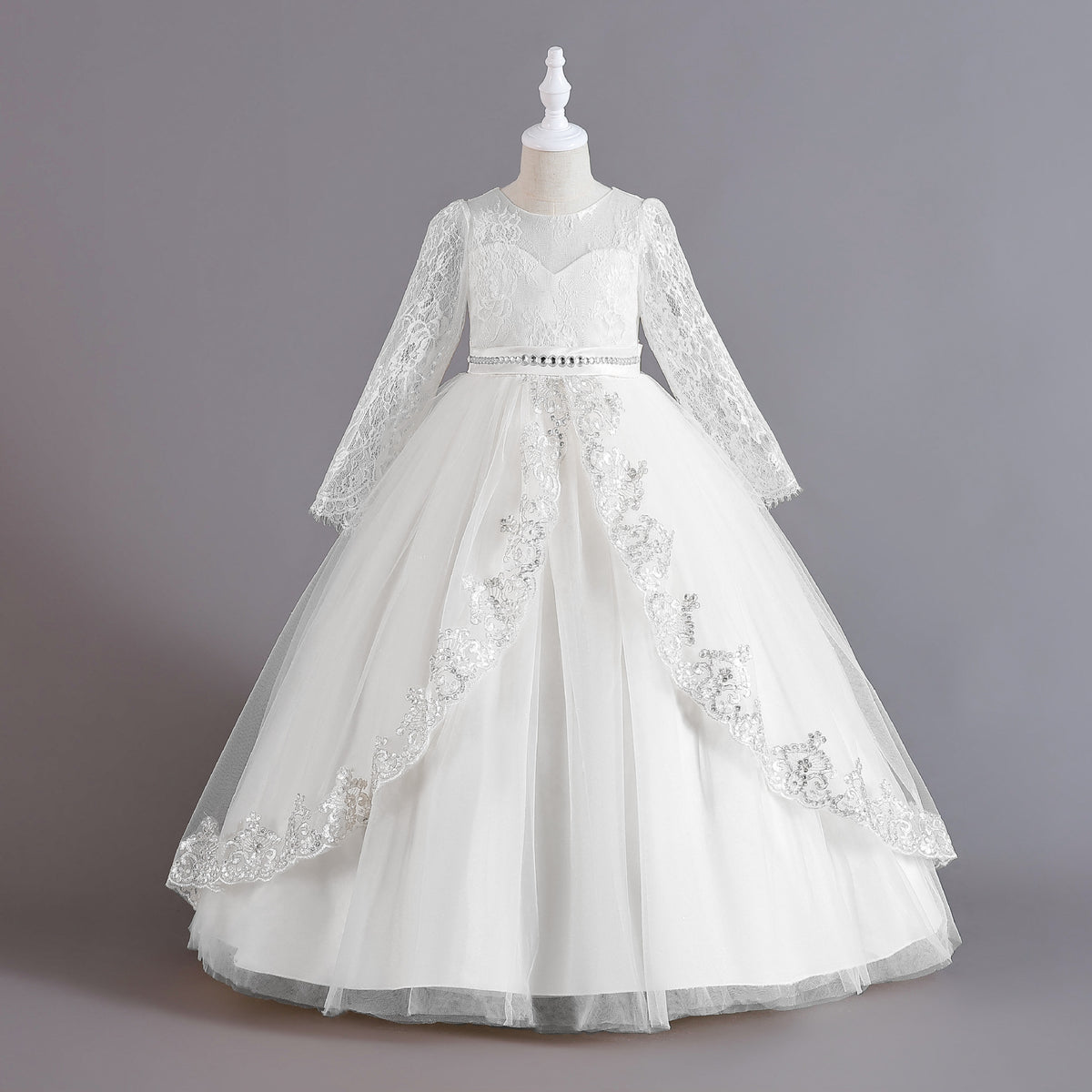 White lace and tulle girls ball gown with long sheer lace sleeves, sequin lace overlay trim and rhinestone waistband, designed for weddings and Christmas.