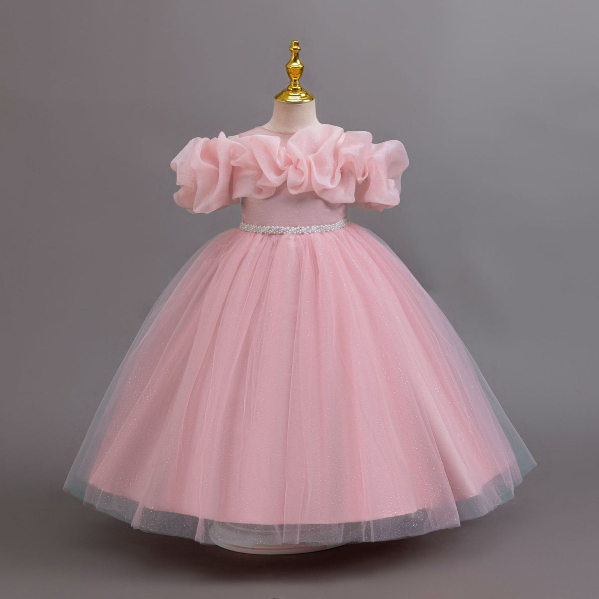 Pink glitter tulle girls ball gown with an off-shoulder ruffle neckline, pearl beaded waist and back bow, designed for birthdays, weddings and flower girls.