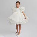 White organza girls dress with short puff sleeves and a full knee-length skirt, designed for flower girls and birthdays.