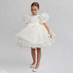 White organza girls dress with short puff sleeves and a full knee-length skirt, designed for flower girls and birthdays.