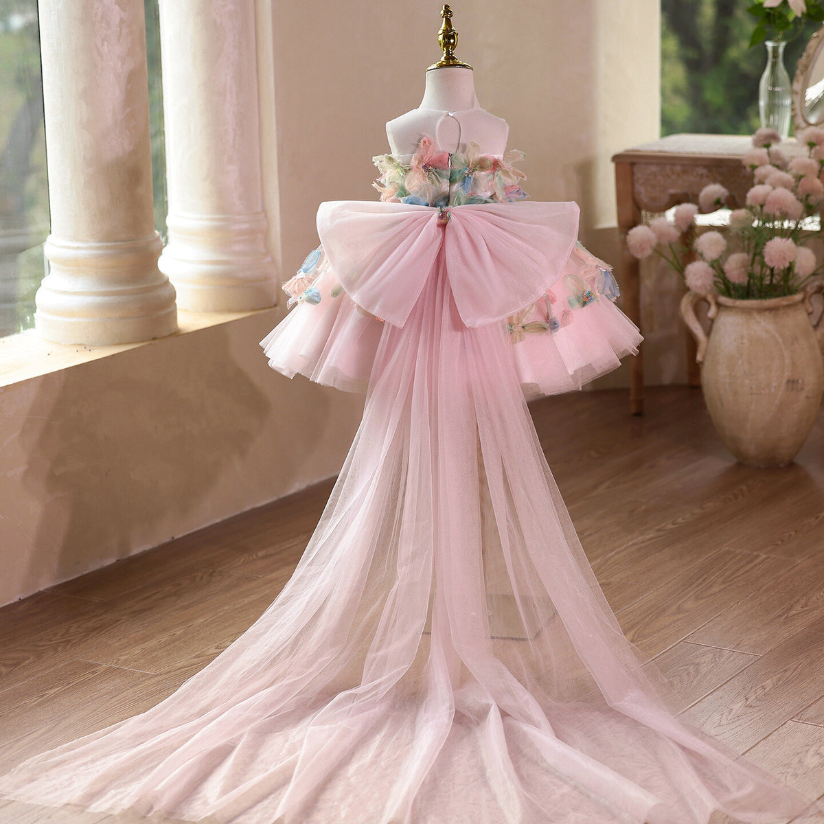 Back view of the pink floral girls party dress showing the oversized tulle bow and the long sheer train.
