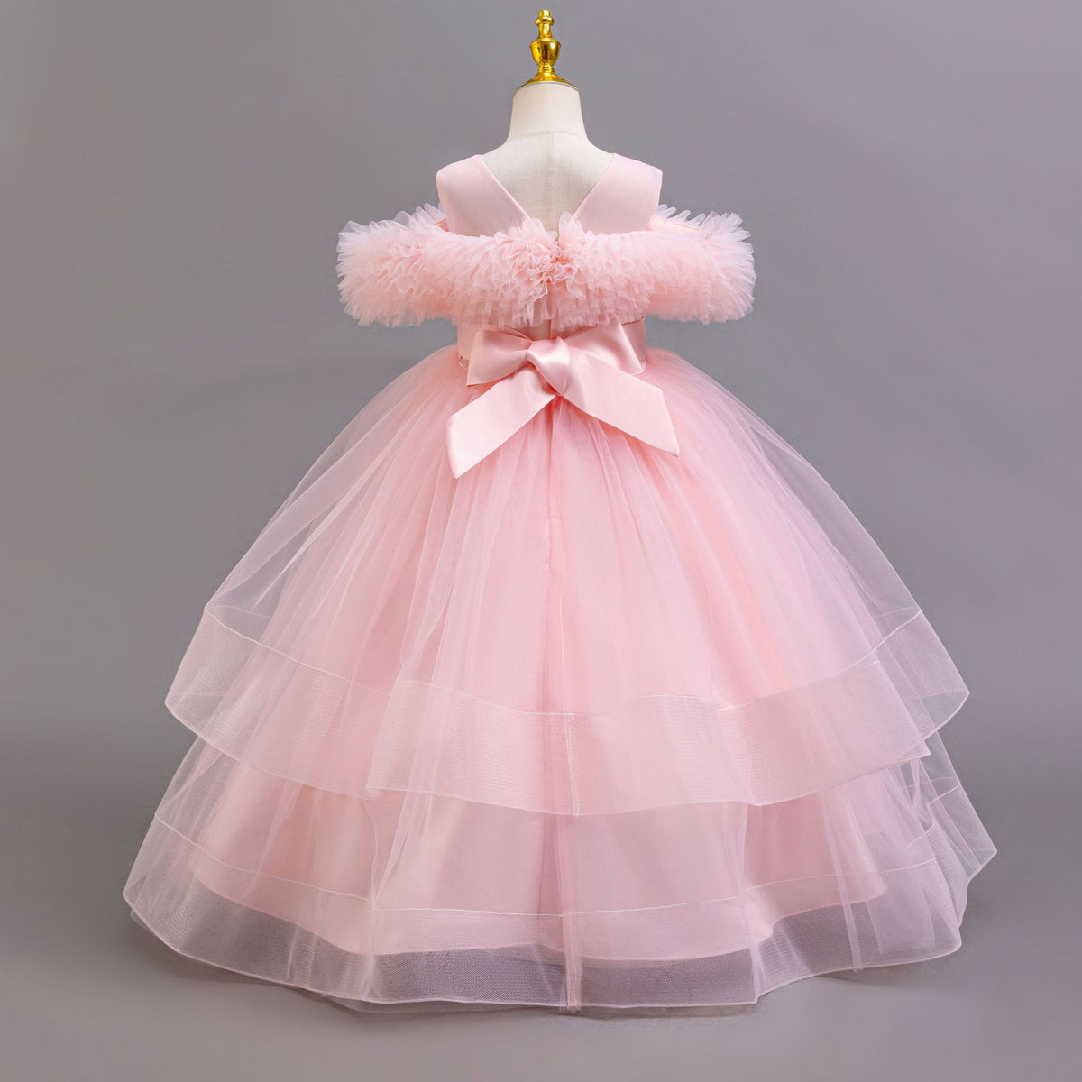 Pink tulle girls ball gown with V back and large satin bow, designed for weddings and flower girls.