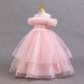 Pink tulle girls ball gown with off-shoulder ruffle neckline, beaded lace waist and three-tier skirt, designed for weddings and flower girls.