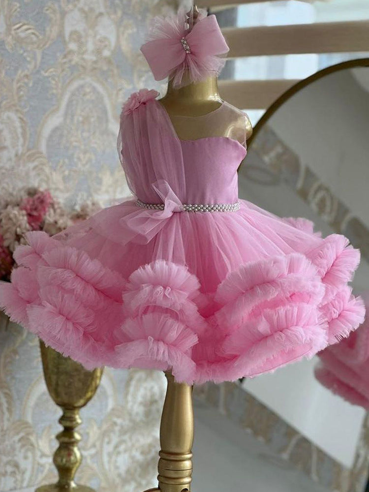 Pink tulle girls one-shoulder dress with pearl beaded waist and tiered ruffle skirt, designed for birthdays, pageants and princess parties.
