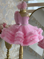 Pink tulle girls one-shoulder dress with pearl beaded waist and tiered ruffle skirt, designed for birthdays, pageants and princess parties.