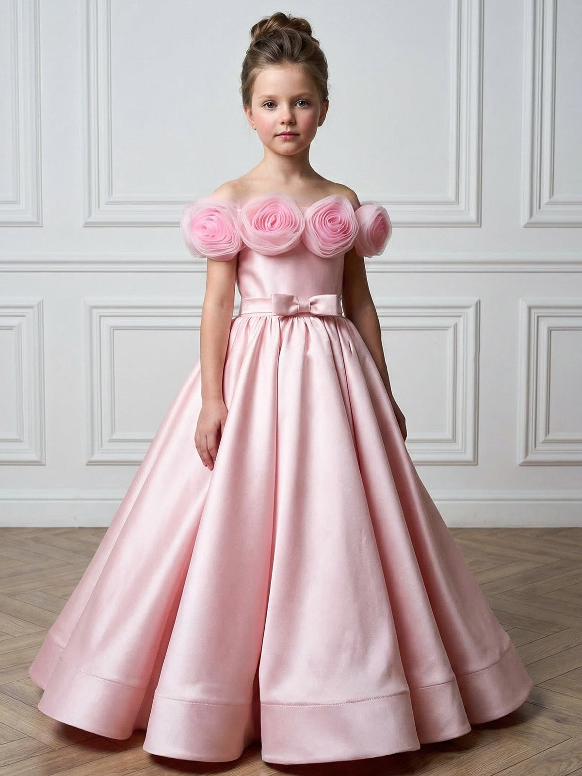 Pink satin girls gown with off-shoulder tulle rosettes and a waist bow, designed for weddings and flower girl duties.