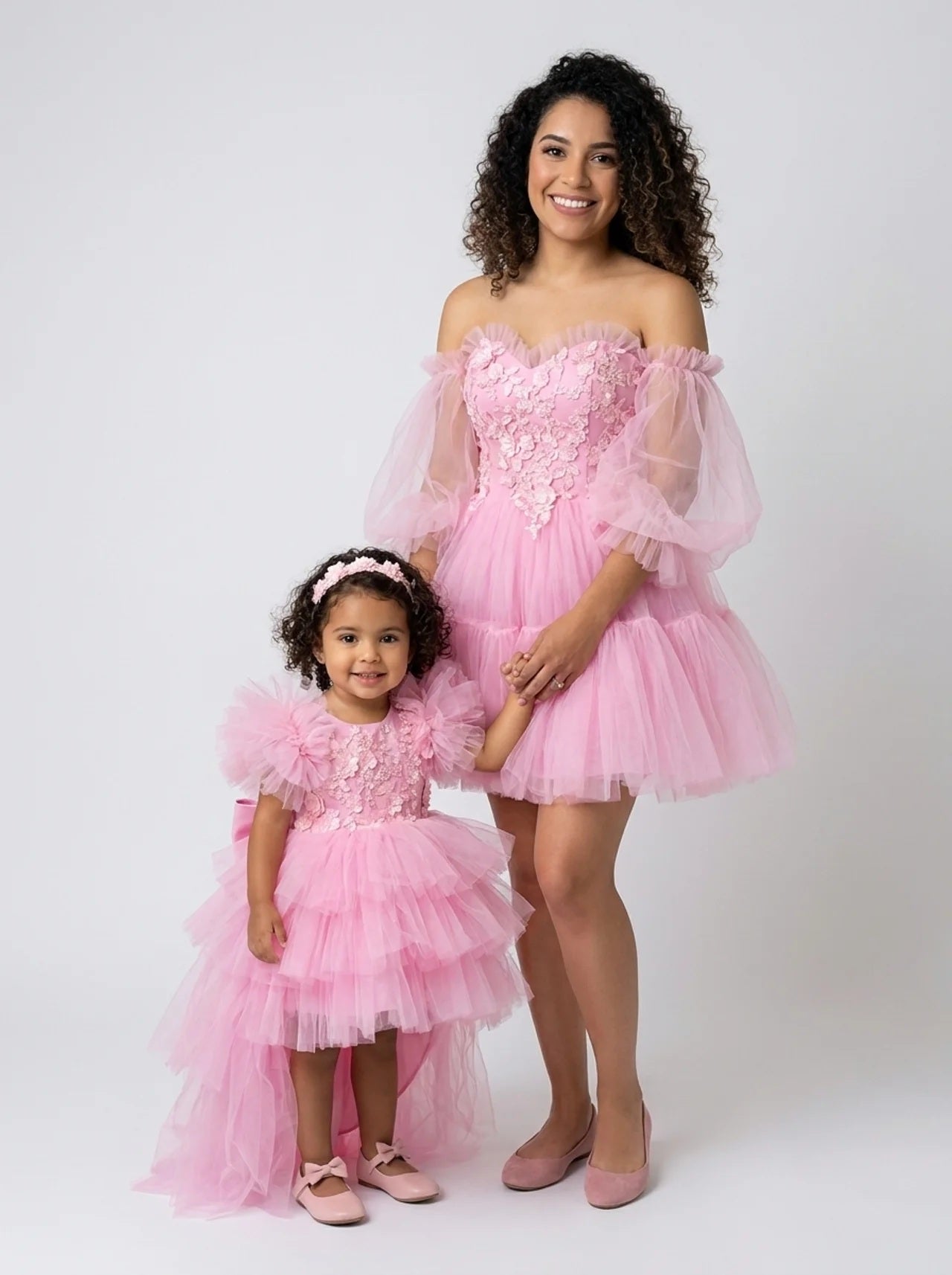 Mother and daughter in matching pink tiered tulle dresses with floral applique bodices, front view