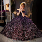 Girl seated in the purple sequin ball gown with the skirt spread around her, for a recital.