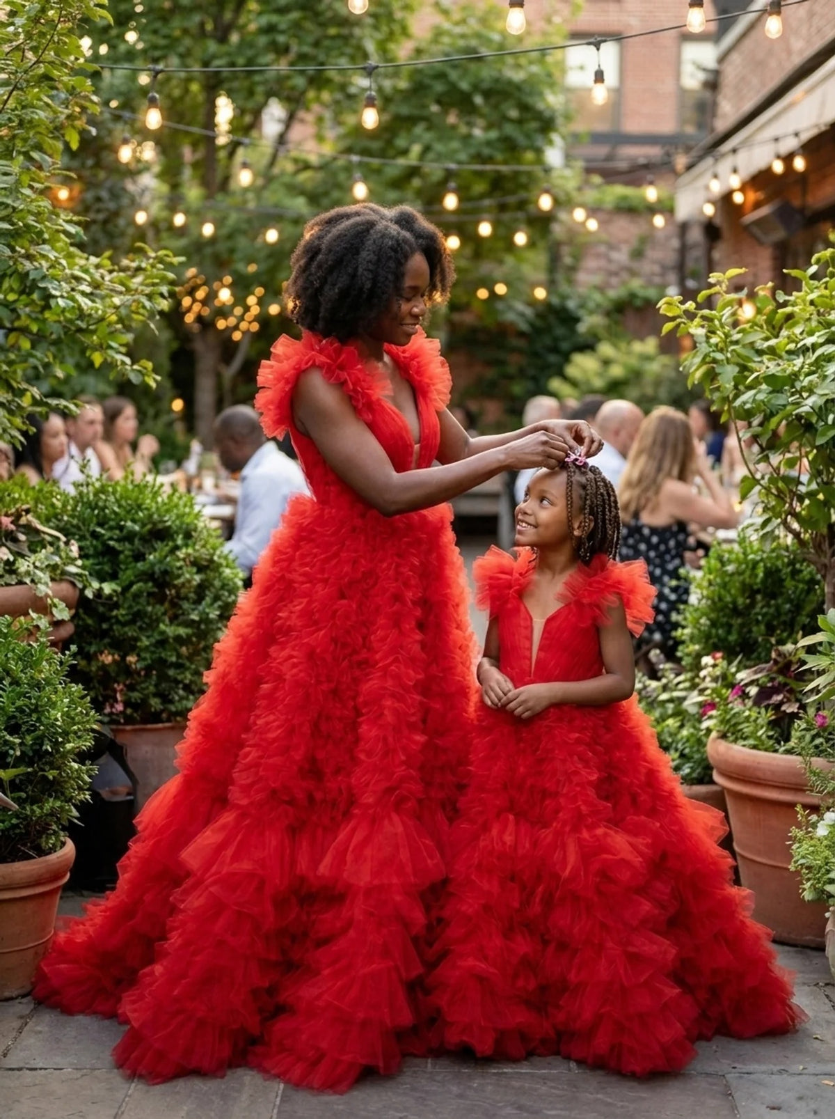 Mother and daughter in matching red tulle ball gowns at a garden evening party