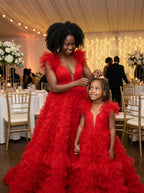 Mother adjusting her daughter's hair at a wedding reception, both in matching red ruffled tulle gowns