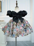 Black satin girls party dress with an oversized front bow, puff sleeves and a 3D floral skirt, designed for birthday parties.