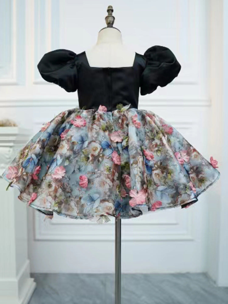 Black satin girls party dress back view with a square neckline, puff sleeves and full floral skirt, designed for birthday parties.