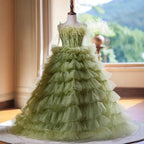 Sage green tulle flower girl dress with a feather trimmed bodice and tiered ruffle skirt, front view, for a wedding.
