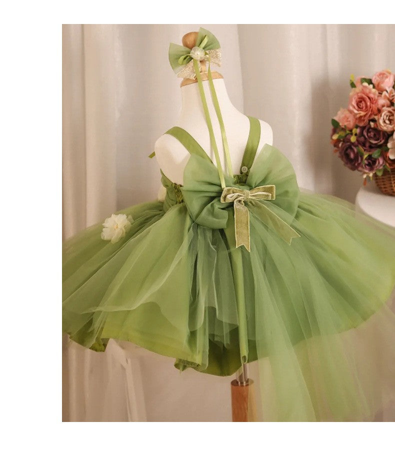 Sage green flower girl dress seen from behind at an angle, showing the button back and the full tutu skirt.