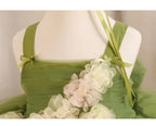 Close-up of the flat shoulder straps and tiny ribbon bows on the sage green flower girl dress.