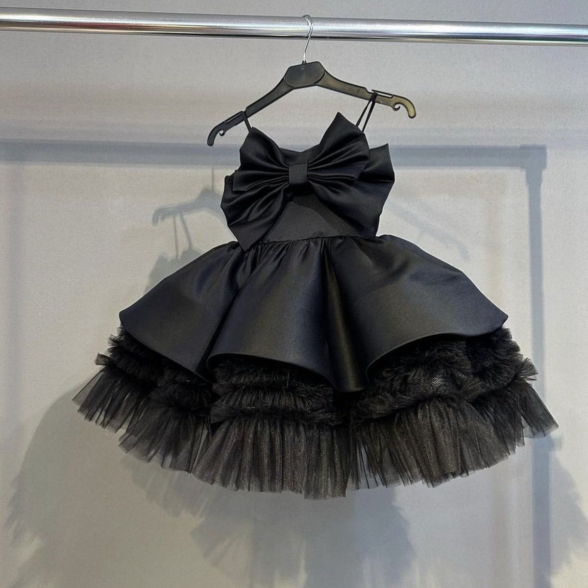 Black satin bow party dress for girls showing the spaghetti straps and two-tier satin skirt, front view 2, for pageants.