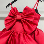 Close-up of the red satin bow bodice and narrow straps on the red birthday girls dress.