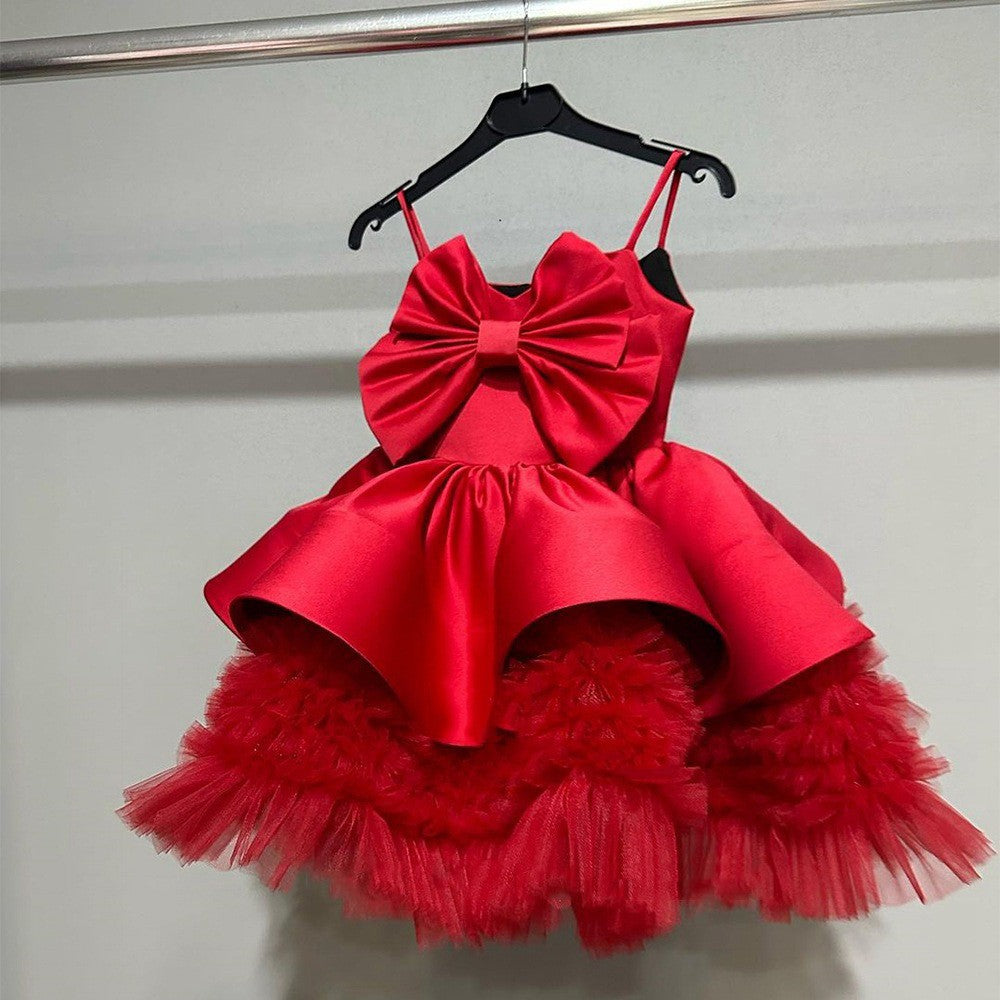 Red satin girls party dress with a large center bow and ruffled tulle underskirt, front view, for birthday celebrations.