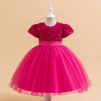 Fuchsia sequin and tulle girls party dress with short puff sleeves, satin waistband and back bow, designed for birthdays and holiday parties.