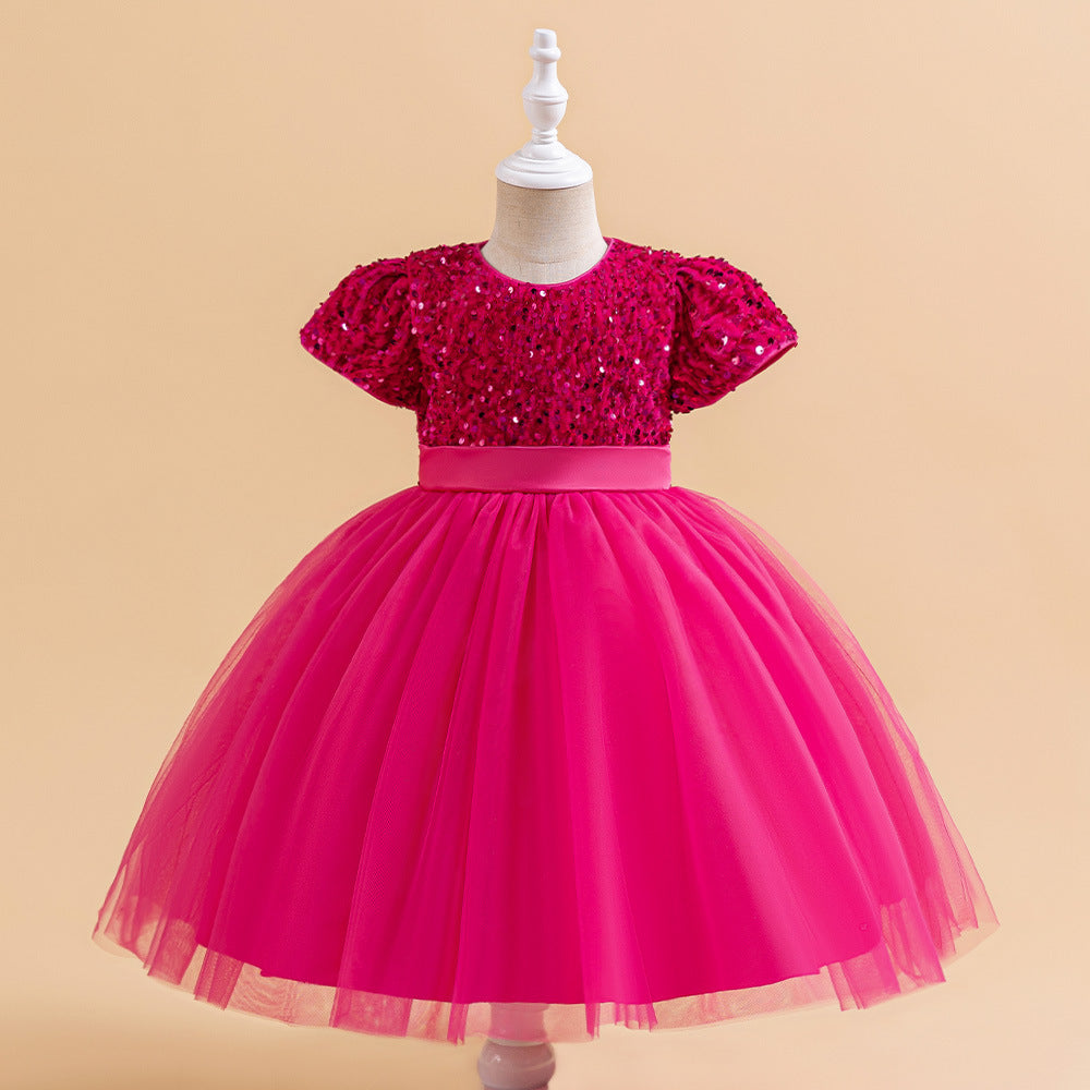 Fuchsia sequin and tulle girls party dress with short puff sleeves, satin waistband and back bow, designed for birthdays and holiday parties.