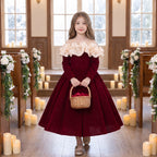 Flower girl in a red velvet dress with ivory ruffles holding a basket of rose petals at a winter wedding