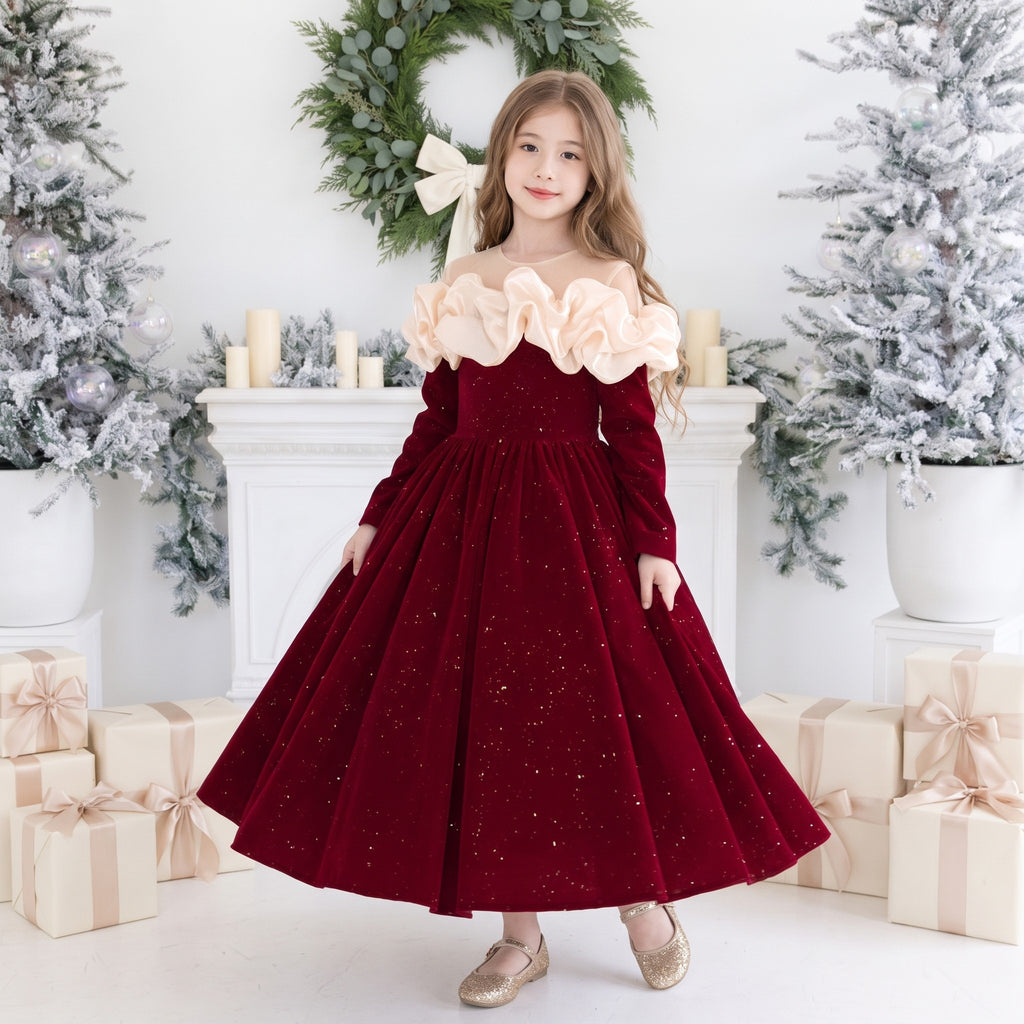 Girl wearing a red sparkle velvet Christmas gown with an ivory satin ruffle collar and long sleeves, front view in a Christmas studio