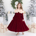 Girl wearing a red sparkle velvet Christmas gown with an ivory satin ruffle collar and long sleeves, front view in a Christmas studio