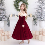 Side view of a girls red velvet ball gown with puffy ivory ruffles over the shoulders and a full sparkle skirt