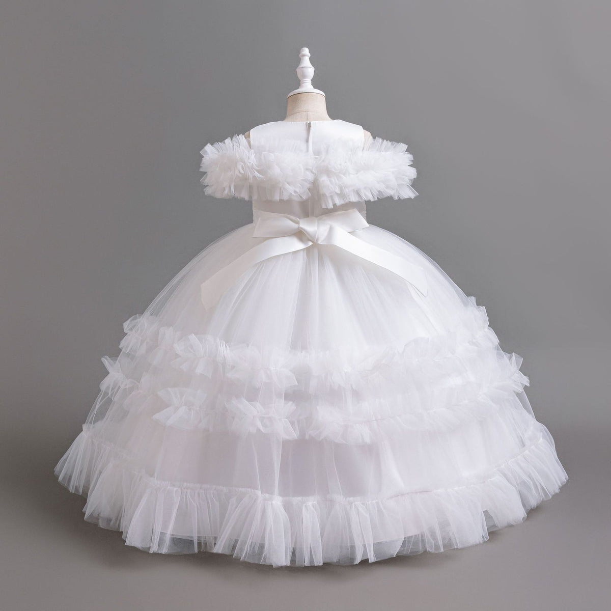White tulle girls ball gown with satin back bow and tiered ruffle skirt, designed for flower girls and weddings.