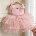 Pink tulle girls party dress with bow shoulder straps and a tiered tutu skirt, front view, for a birthday party.