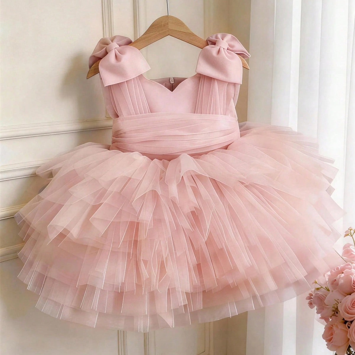 Pink tulle girls party dress with bow shoulder straps and a tiered tutu skirt, front view, for a birthday party.