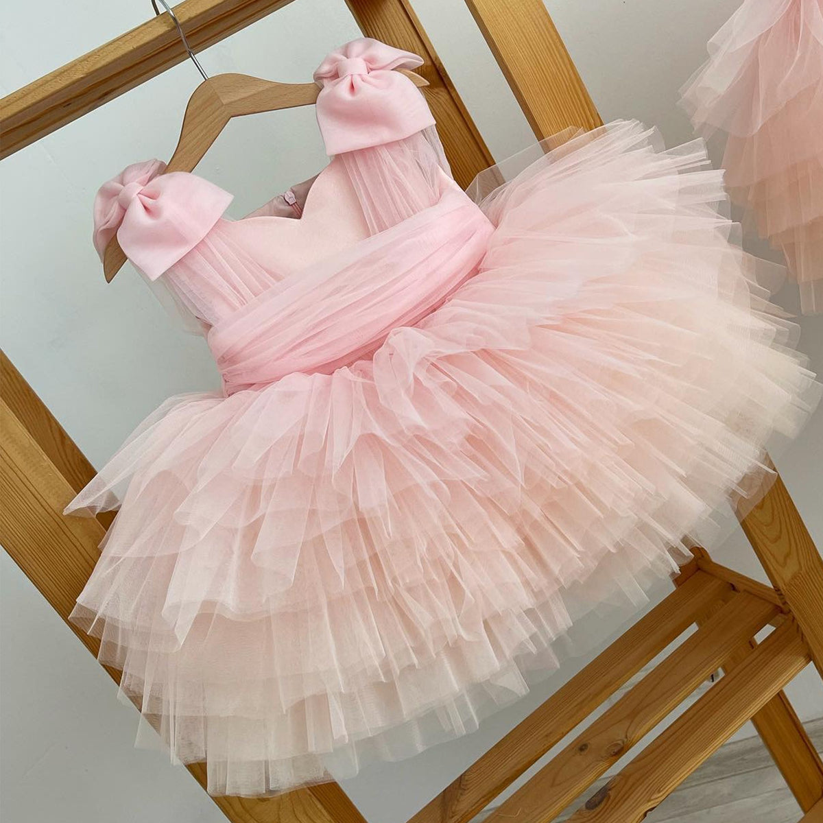 Pink tiered tulle princess dress styled on a wooden ladder, angled view, one of our birthday girls dresses.